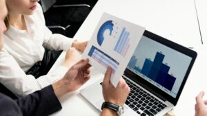 Business meeting analyzing charts on laptop screen