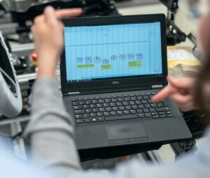 Engineers analyzing diagrams on a laptop in factory.