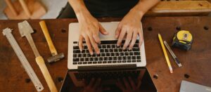 Person using laptop on wooden workshop table