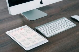 iMac, tablet with calendar, keyboard on desk