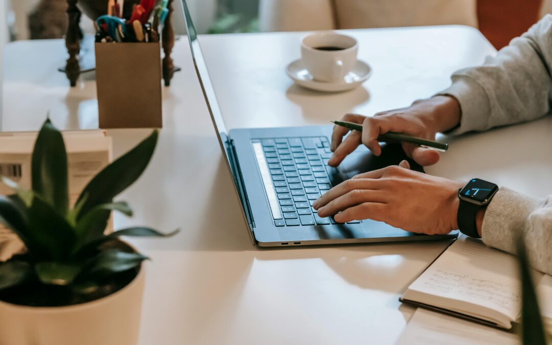 Person typing on laptop at desk with coffee