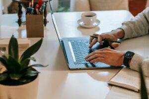 Person typing on laptop at desk with coffee